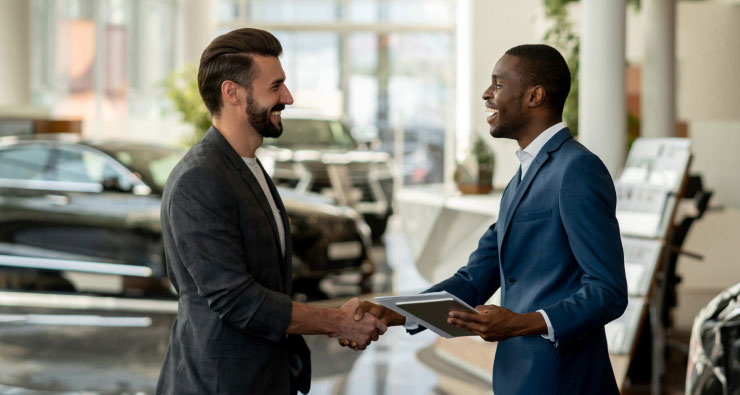 Image of dealership staff shaking hands in the showroom