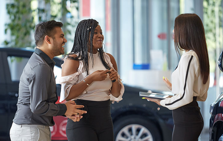 Image of a couple meeting with the dealership sales manager on the showroom floor.