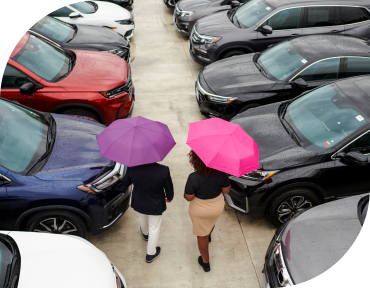 Image of two people with umbrellas in a parking lot.